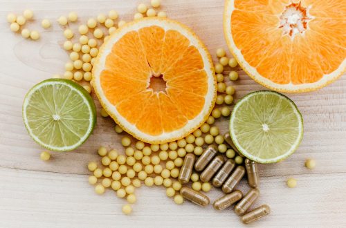 Citrus slices, small yellow supplement beads, and brown capsules on a wooden surface